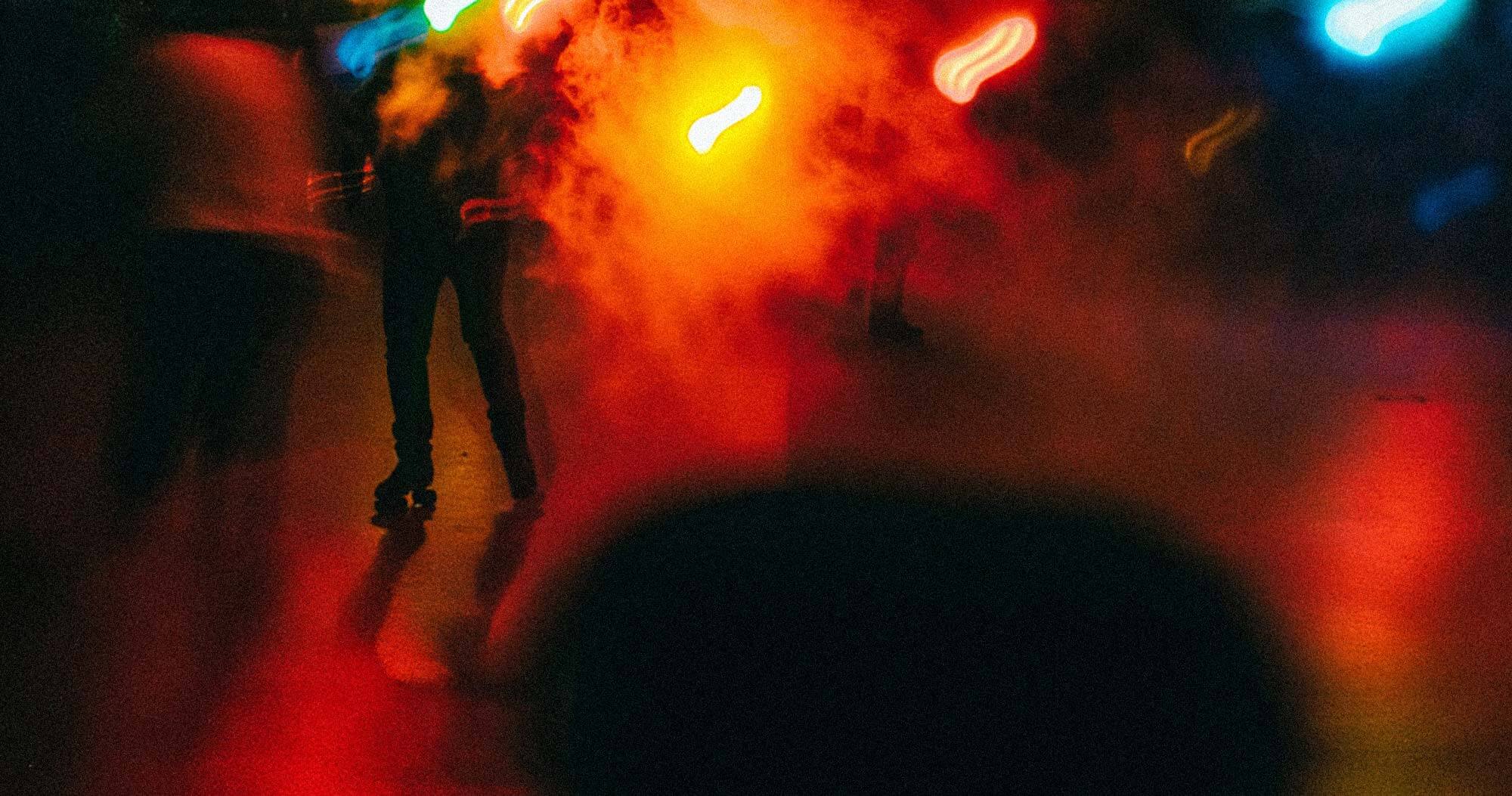 Learn-more-about-roller-skating-Sydney-pitch-details-SKTNG A distorted view of a roller skating rink at night with lights and smoke filling the space